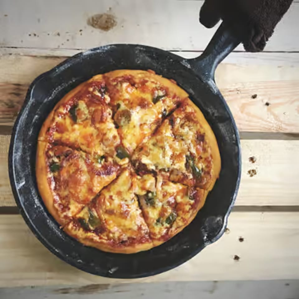 Frankie's Pizza II deep-dish pizza, with melted cheese and toppings, served in a cast-iron skillet.